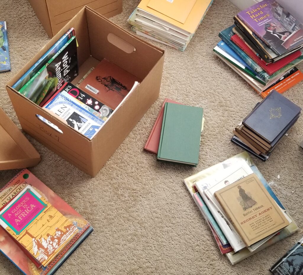 books on the floor around an open box